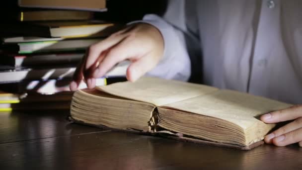 Homem inteligente estudando tarde da noite, ele está sentado na mesa e lendo livro — Vídeo de Stock