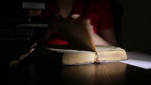 Un hombre inteligente que estudia hasta tarde en la noche, está sentado en el escritorio y leyendo un libro — Vídeos de Stock