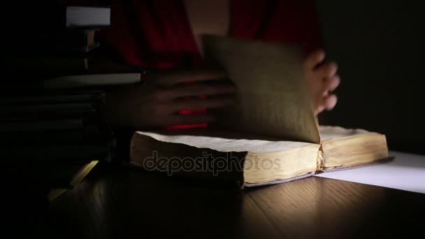 Homme intelligent étudiant tard dans la nuit, il est assis au bureau et lit le livre 