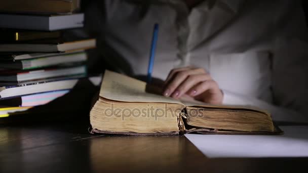 Homem inteligente estudando tarde da noite, ele está sentado na mesa e lendo livro — Vídeo de Stock