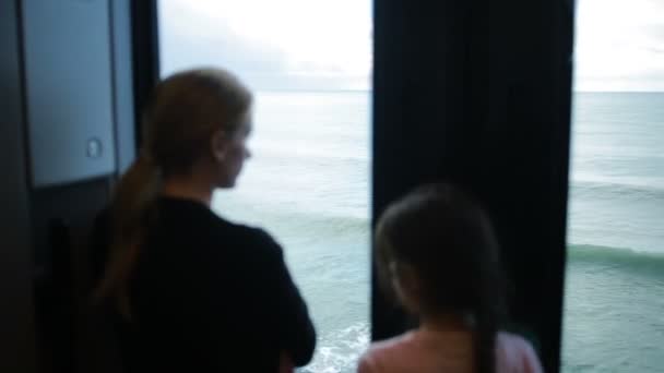 Семья путешествует на поезде и смотрит в окно на море — стоковое видео