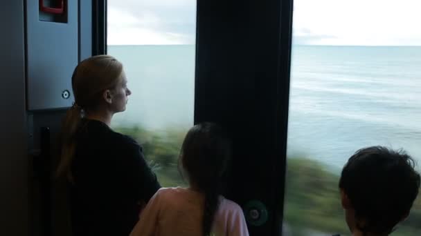 Family traveling on a train and looks through the window at the sea — Stock Video