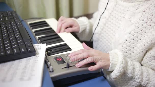 女性は、コンピューター上の音楽を書き込みます。デジタル ピアノ midi キーボード — ストック動画