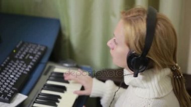 kadın müzik bilgisayar üzerinde yazar. dijital piyano MIDI klavye