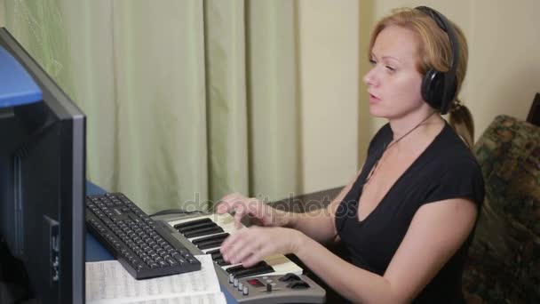 Frau schreibt Musik am Computer. digitale Klaviertastatur midi — Stockvideo