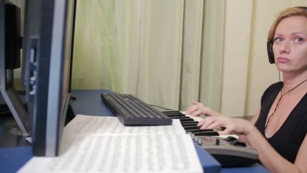 Γυναίκα γράφει μουσική στον υπολογιστή. ψηφιακό πιάνο midi πληκτρολόγιο — Αρχείο Βίντεο
