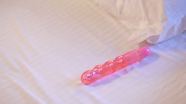Womans hand reaching for dildo in bed. girl with a sex toy
