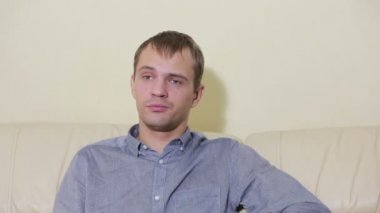 Uzaktan kumandalı bir adam evde televizyon izliyor.