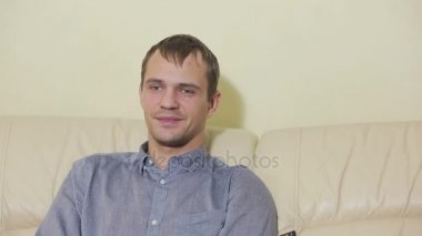 Uzaktan kumandalı bir adam evde televizyon izliyor.