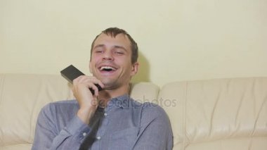 Uzaktan kumandalı bir adam evde televizyon izliyor.