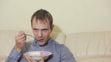 Uzaktan kumandalı bir adam evde televizyon izliyor.