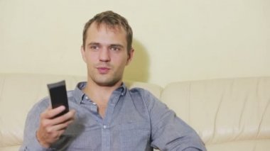 Uzaktan kumandalı bir adam evde televizyon izliyor.