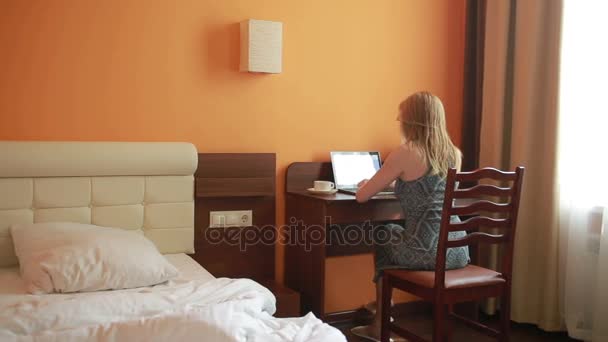 Mooie vrouw bezig met een laptop die zittend op de tafel in het huis. — Stockvideo