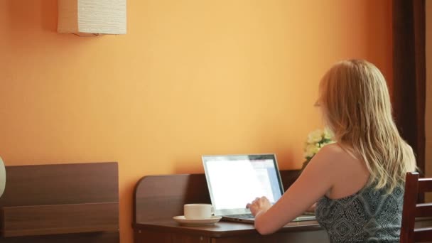 Mooie vrouw bezig met een laptop die zittend op de tafel in het huis. — Stockvideo