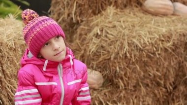 saman üzerinde oturan küçük kız tatil için bekleyen kabakları dekore edilmiş