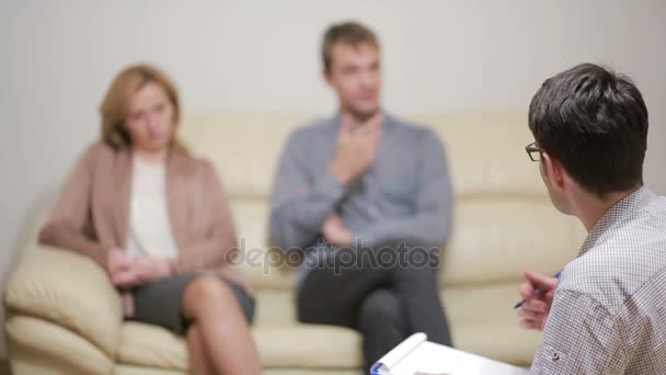 Psicóloga masculina ayudando a pareja joven preocupada. terapia familiar. gente enojada — Vídeos de Stock