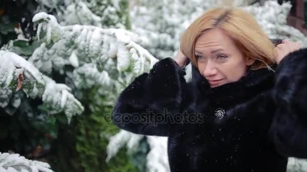 Mulher bonita jovem em casaco de vison elegante em um contexto de um parque de inverno — Vídeo de Stock
