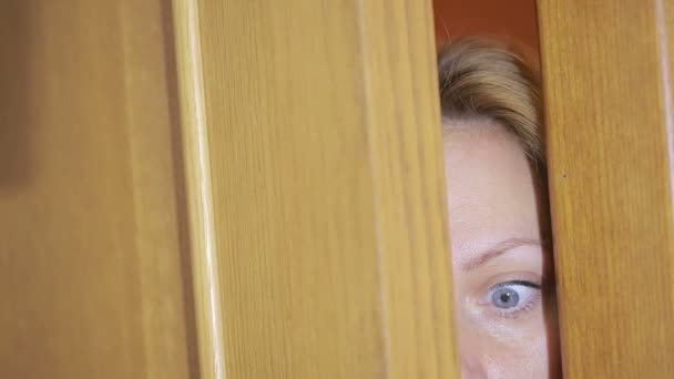 Mädchen spioniert durch einen Türspalt. Auge blickt durch einen Schlitz — Stockvideo