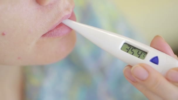 Malade femme avec thermomètre numérique dans la bouche. 36, 8 — Video