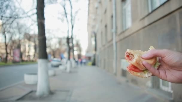 Mujer joven comiendo comida rápida al aire libre — Vídeo de stock