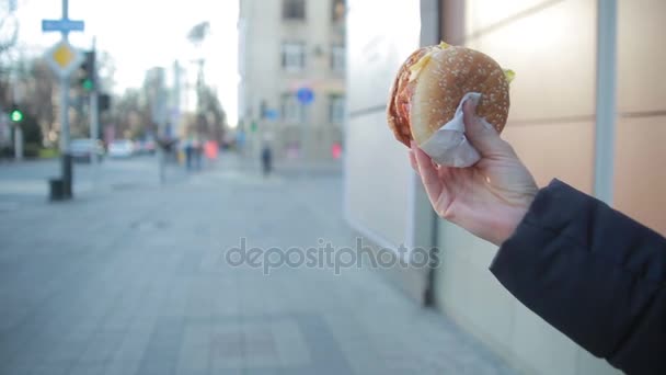 Jovem mulher comer fast food ao ar livre — Vídeo de Stock