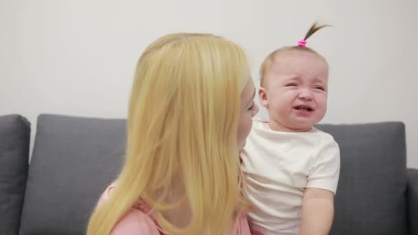Mãe com seu bebê brincando em um sofá na sala de estar — Vídeo de Stock