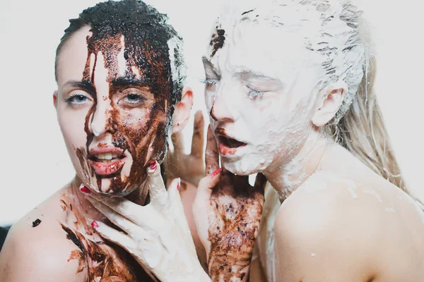 Zwei Mädchen mit weißer und dunkler Schokolade übergossen. Leidenschaftliche Frauen — Stockfoto