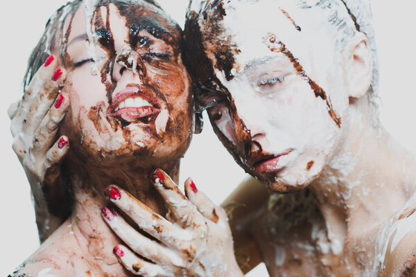 two girls doused with white and dark chocolate. passionate women