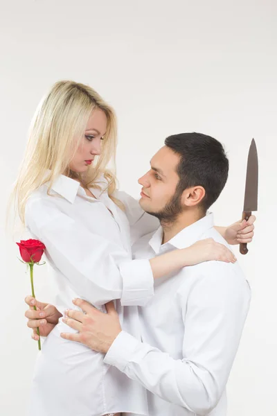 Κοπέλα που κρατά μαχαίρι προδότης. άνθρωπος με τριαντάφυλλο στο χέρι του. — Φωτογραφία Αρχείου