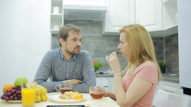 Pareja joven en la cocina. beber té y comer fruta — Vídeo de stock