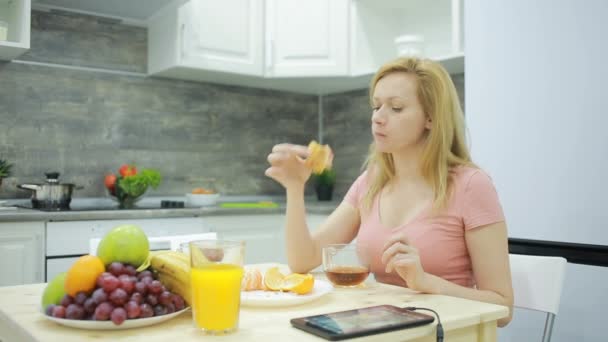 Pirang minum teh dengan croissant di rumahnya di dapur — Stok Video