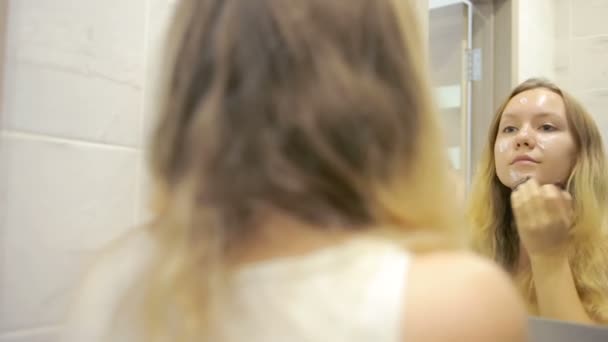 Όμορφη νεαρή γυναίκα κάνει μακιγιάζ μπροστά από τον καθρέφτη. — Αρχείο Βίντεο