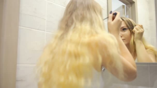 美しい若い女性は、鏡の前で化粧をしています。. — ストック動画