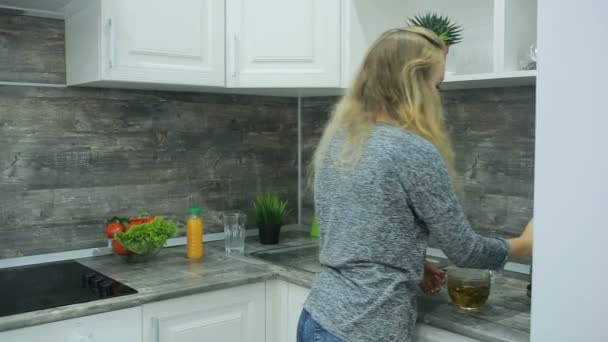 Menina loira bonita comer e beber comida saudável em casa, conceito de cuidados de saúde — Vídeo de Stock