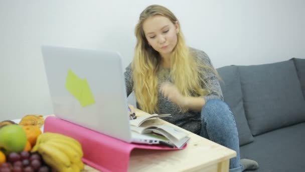 Fiatal lány diák csinál házi feladatot otthon a kanapén — Stock videók