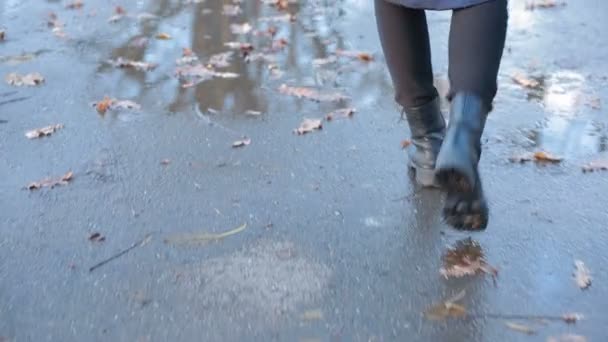 Fille portant des bottes de combat noires éclaboussant dans une flaque après la pluie — Video