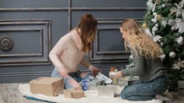 Örme kazak kürk üzerinde oturan iki genç kadın yakın: yeni yıl ağacı