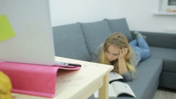 Молодая девушка студентка делает домашнее задание дома на диване — стоковое видео