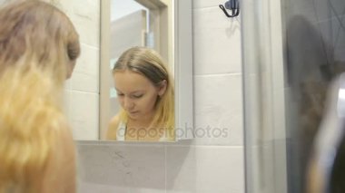 Güzel genç kadın aynanın önünde makyaj yapıyor.