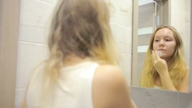 Güzel genç kadın aynanın önünde makyaj yapıyor.