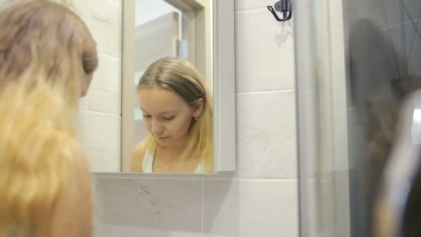 Hermosa joven mujer está haciendo maquillaje delante del espejo . — Vídeo de stock