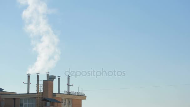 Fumée des cheminées des maisons de ville sur fond de ciel bleu — Video