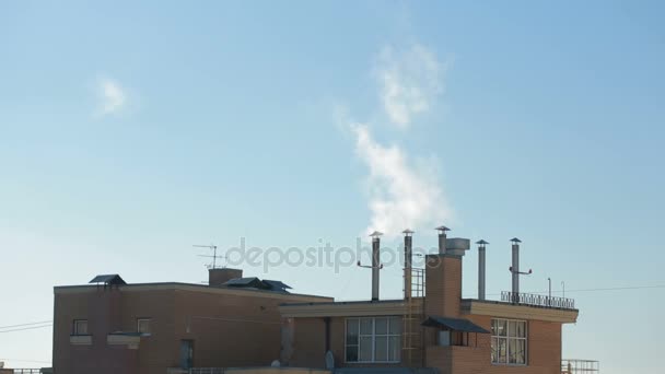 Fumée des cheminées des maisons de ville sur fond de ciel bleu — Video