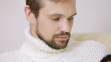 bir tablet ile kanepede ceketli genç sakallı adamı