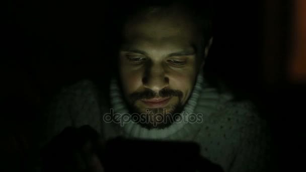ひげと暗闇の中でタブレットのセーターを持つ男 — ストック動画
