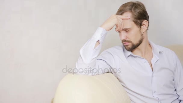 Портрет хлопця, який дивиться на камеру на дивані. Молодий чоловік з сорочкою розслабляється вдома — стокове відео