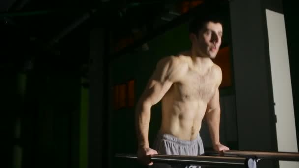 Muscular hombre banco realiza en los bares irregulares en el gimnasio . — Vídeos de Stock