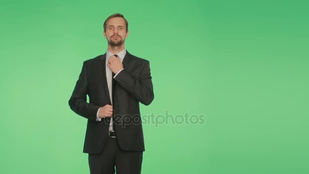 Körpersprache. Mann auf grünem Hintergrund. glättet Krawatte, flirtet. — Stockvideo