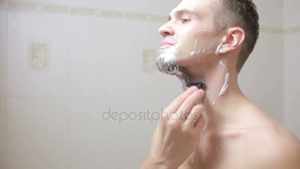 男はバスルームにかみそりでひげを剃る、笑みを浮かべて — ストック動画
