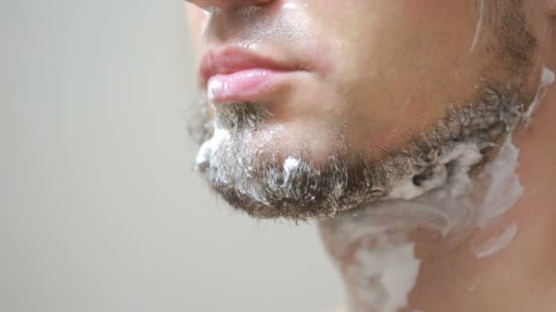 Kille rakar bort sitt skägg med en rakhyvel i badrummet och leende — Stockvideo